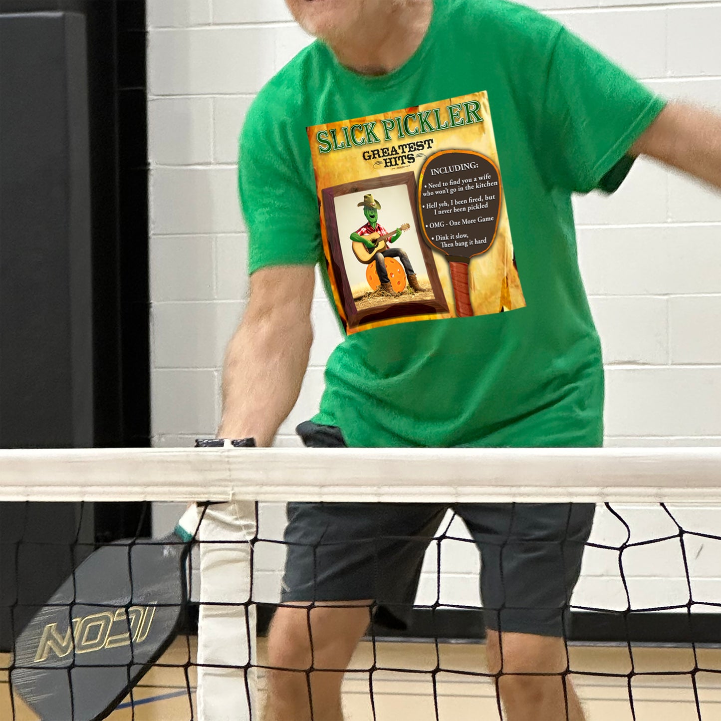 Man playing pickleball wearing Green t-shirt with Slick Pickler design